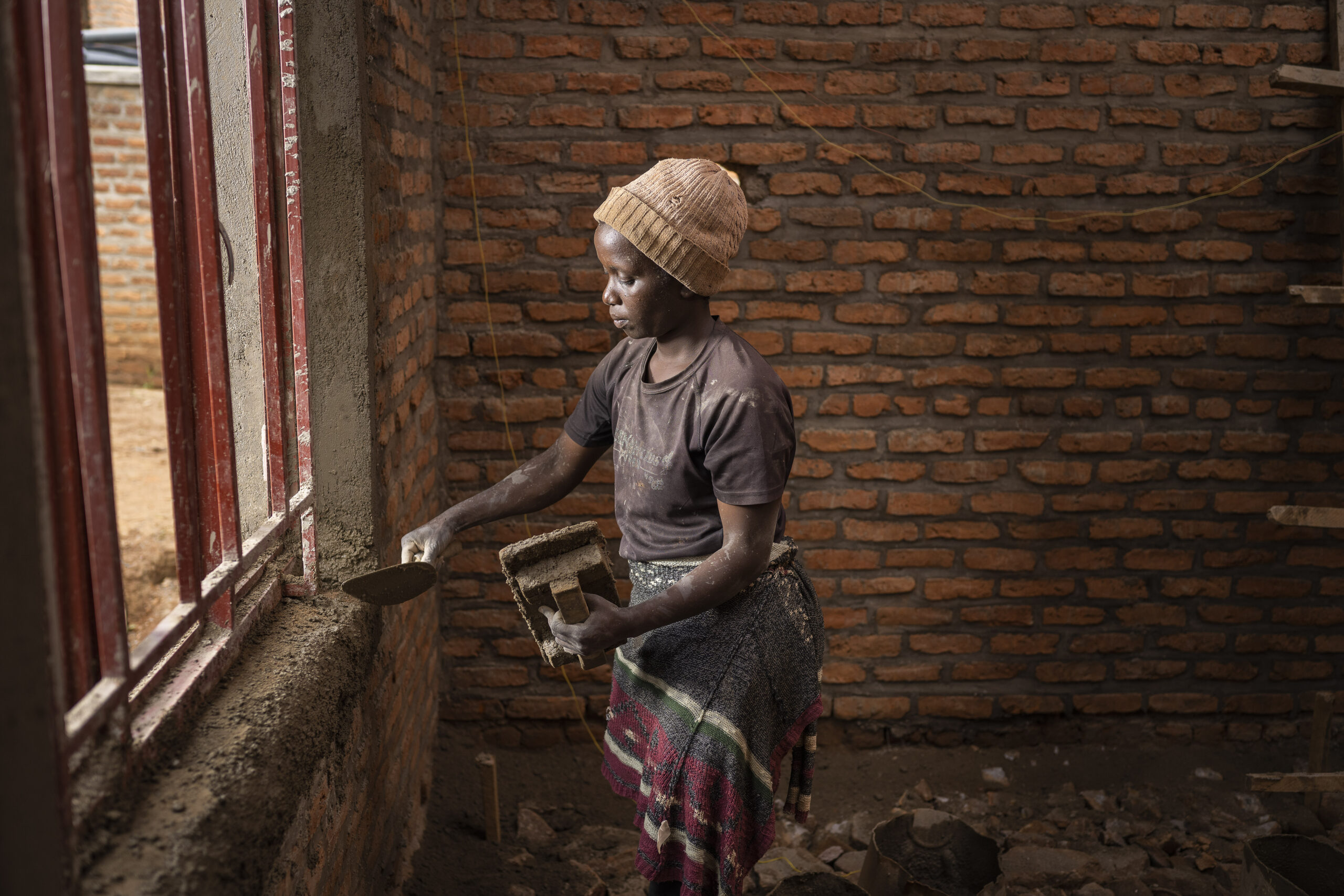Rwanda, female construction workers. Uwiduhaye Pacifique (in black T-shirt), at construction site in Kigali. Building will host administrative services of the military veterans organisation.
